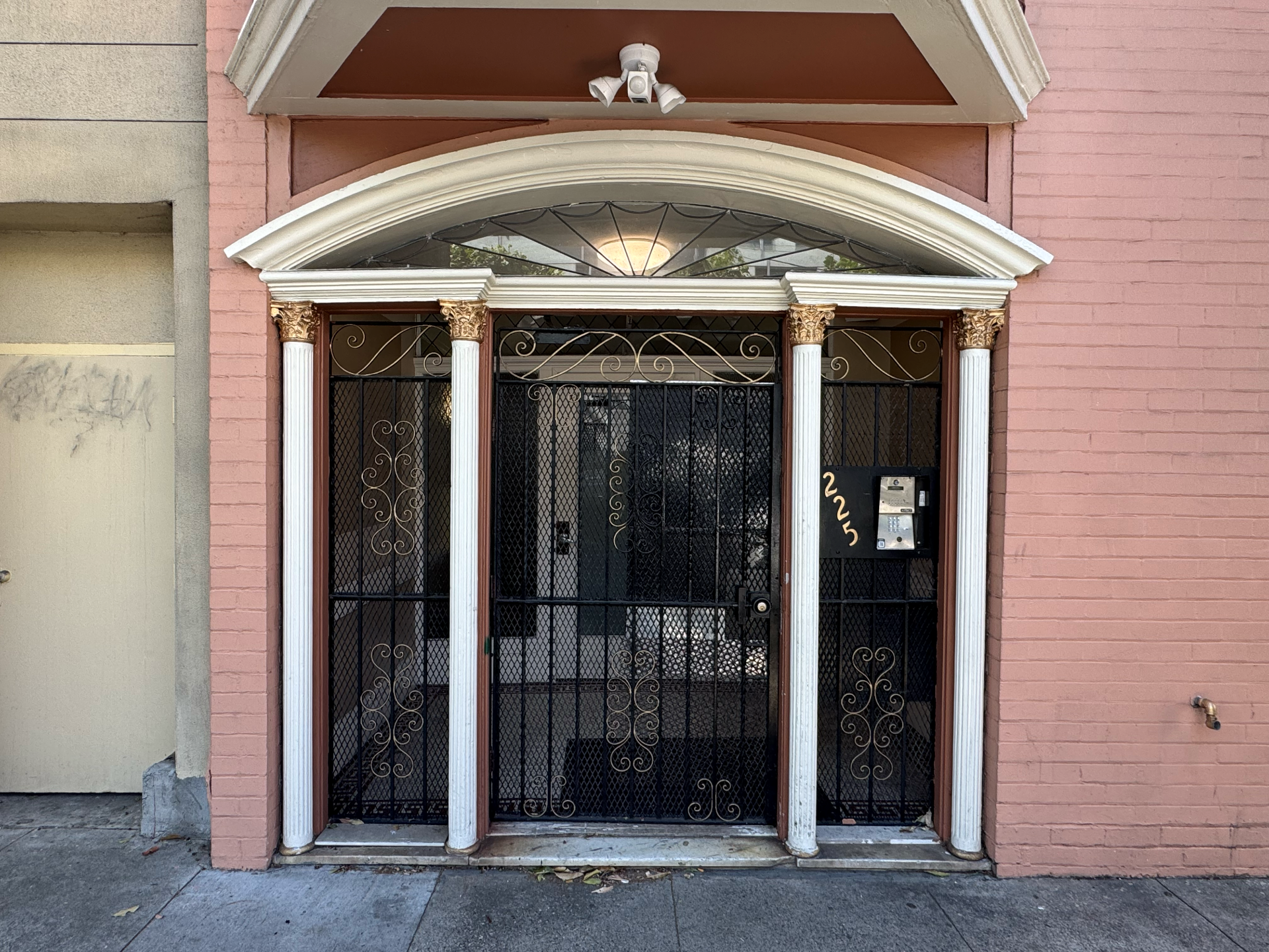 A pink building with a black gate and white columns.